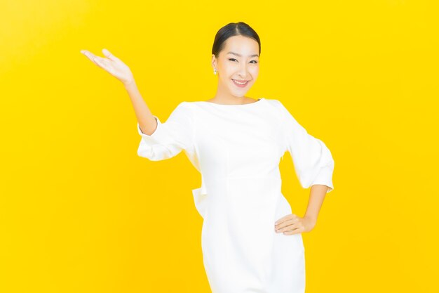 Portrait beautiful young asian woman smile with action on yellow