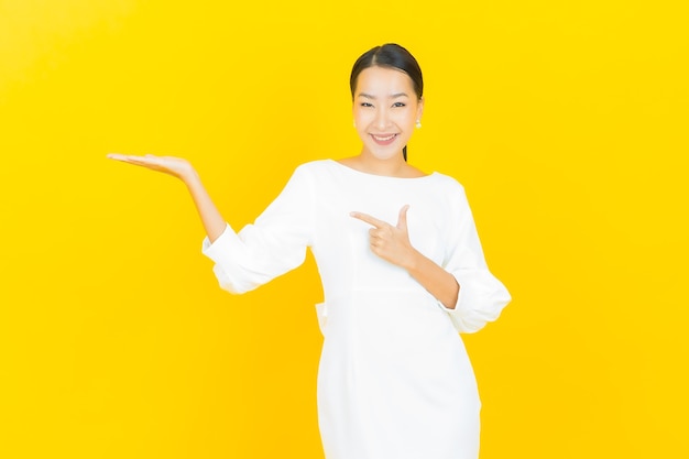 Portrait beautiful young asian woman smile with action on yellow