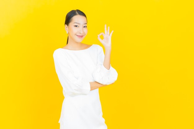 Portrait beautiful young asian woman smile with action on yellow