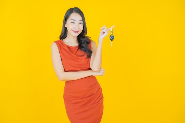 Portrait beautiful young asian woman smile with car key on yellow