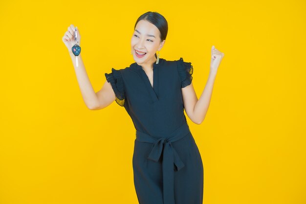 Portrait beautiful young asian woman smile with car key on yellow