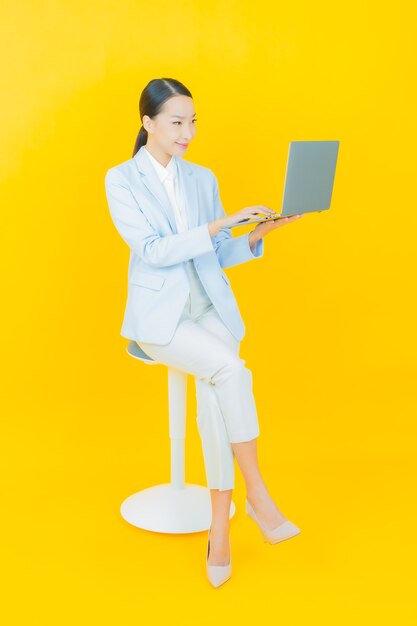 孤立した背景の上のコンピューターのラップトップと肖像画美しい若いアジアの女性の笑顔