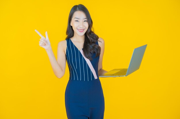 孤立した背景の上のコンピューターのラップトップと肖像画美しい若いアジアの女性の笑顔