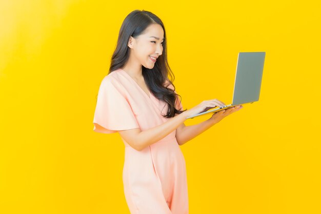 외진 벽에 컴퓨터 노트북을 들고 웃고 있는 아름다운 젊은 아시아 여성 초상화