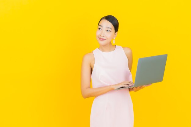 노란색에 컴퓨터 노트북과 세로 아름 다운 젊은 아시아 여자 미소