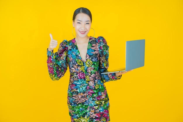 Portrait beautiful young asian woman smile with computer laptop on on yellow