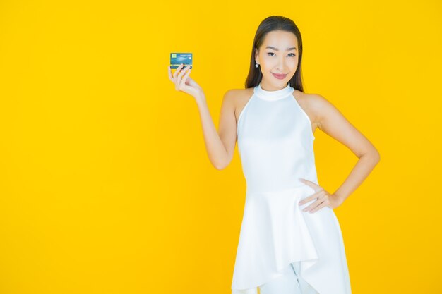 노란색에 신용 카드와 함께 초상화 아름 다운 젊은 아시아 여자 미소