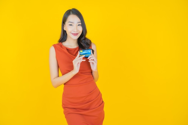 Ritratto bella giovane donna asiatica sorriso con carta di credito su yellow