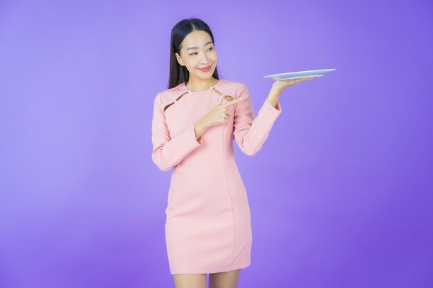 Portrait beautiful young asian woman smile with empty plate dish on color background