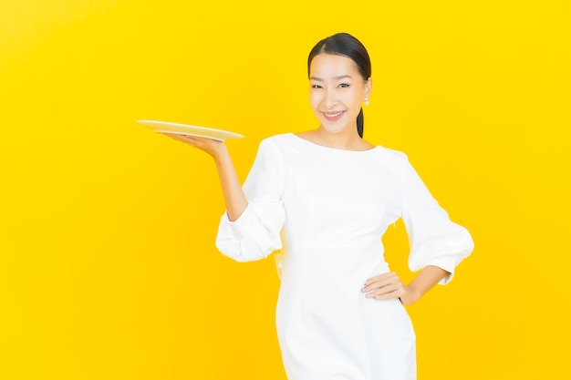 노란색에 빈 접시 접시와 초상화 아름 다운 젊은 아시아 여자 미소