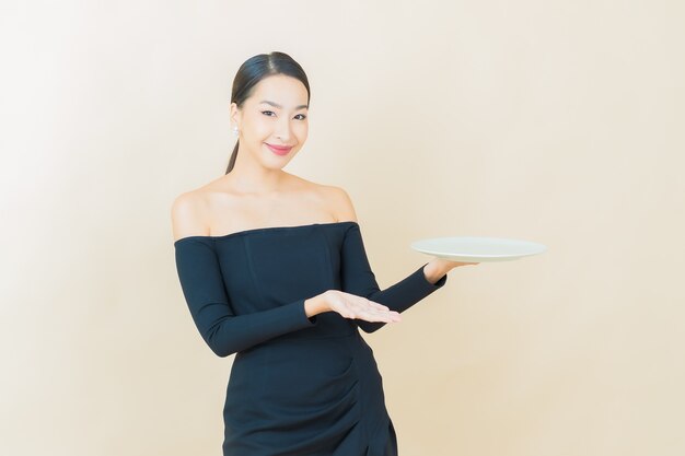 Portrait beautiful young asian woman smile with empty plate dish on yellow