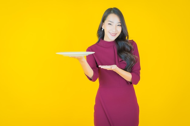 노란색에 빈 접시 접시와 함께 초상화 아름 다운 젊은 아시아 여자 미소