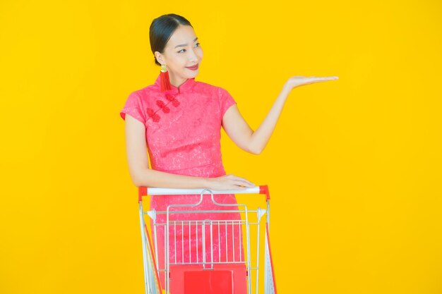 Portrait beautiful young asian woman smile with grocery basket from supermarket on color background