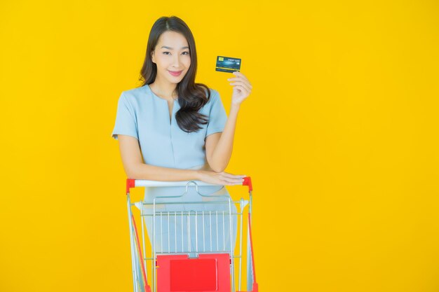 Portrait beautiful young asian woman smile with grocery basket from supermarket on color background