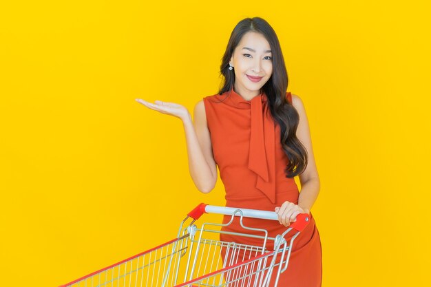 黄色のスーパーマーケットからの食料品バスケットと肖像画美しい若いアジアの女性の笑顔