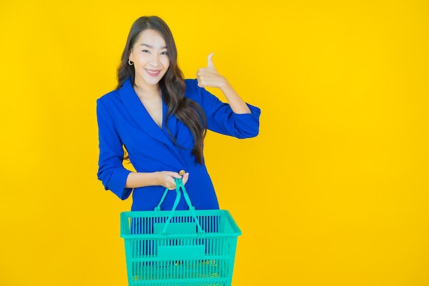 Ritratto bella giovane donna asiatica sorriso con cesto della spesa dal supermercato su yellow