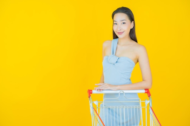 Portrait beautiful young asian woman smile with grocery basket from supermarket on yellow