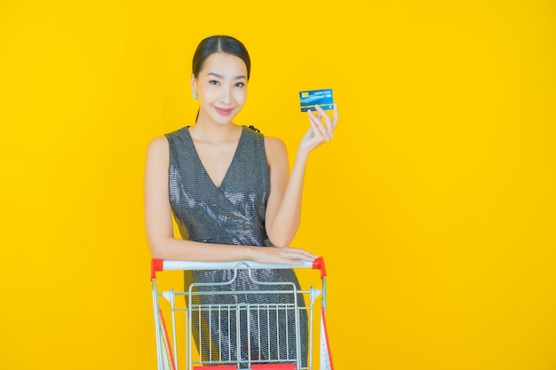 노란색 슈퍼마켓에서 식료품 바구니를 들고 웃는 아름다운 젊은 아시아 여성