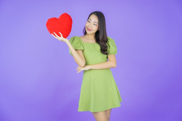 색상 배경에 심장 베개 모양으로 웃는 초상화 아름다운 젊은 아시아 여성