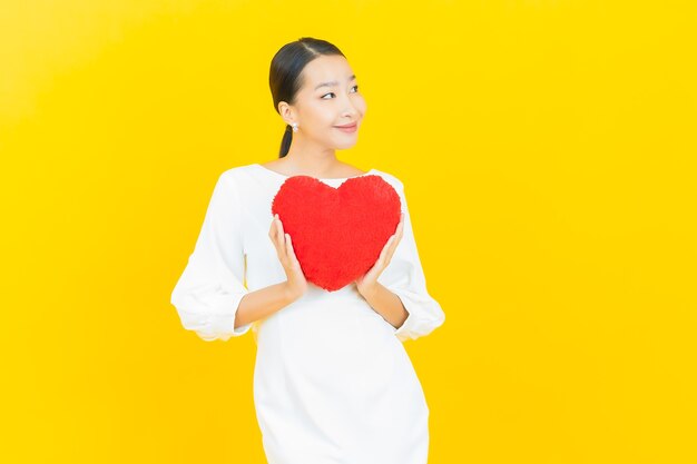 노란색에 심장 베개 모양의 초상화 아름 다운 젊은 아시아 여자 미소