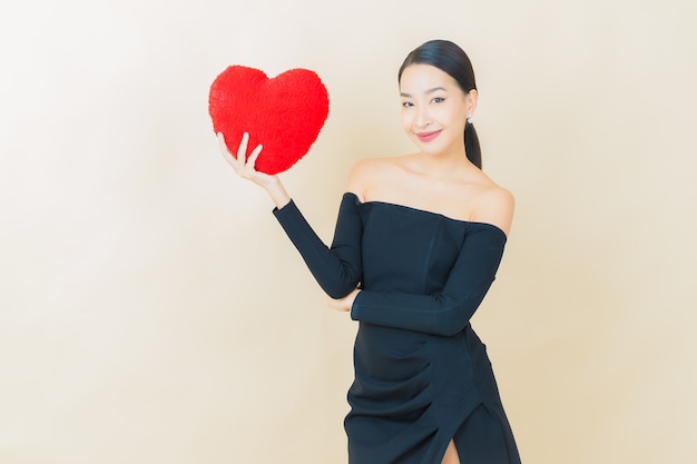 Улыбка женщины портрета красивая молодая азиатская с формой подушки сердца на желтом