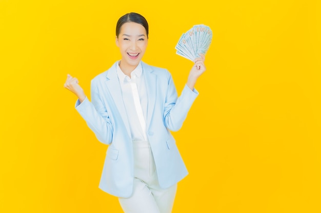 Portrait beautiful young asian woman smile with a lot of cash and money on yellow