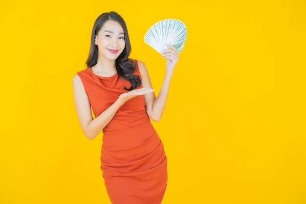 Portrait beautiful young asian woman smile with a lot of cash and money on yellow