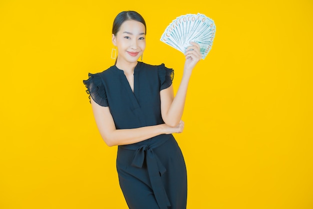 Portrait beautiful young asian woman smile with a lot of cash and money on on yellow