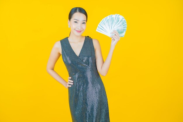 Portrait beautiful young asian woman smile with a lot of cash and money on yellow