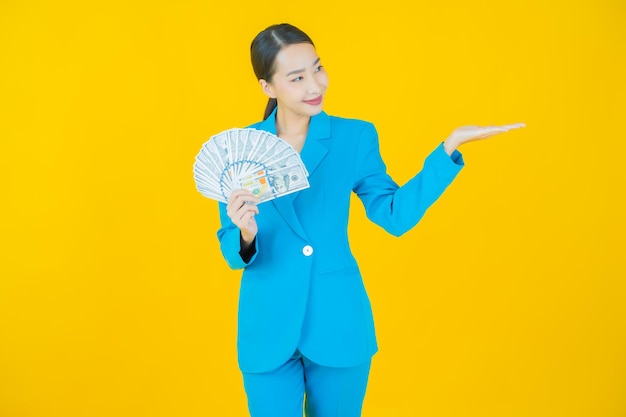 Portrait beautiful young asian woman smile with a lot of cash and money on yellow