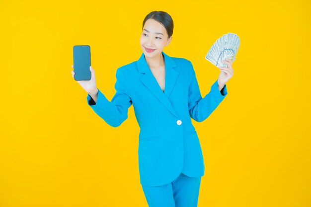 Portrait beautiful young asian woman smile with a lot of cash and money on yellow