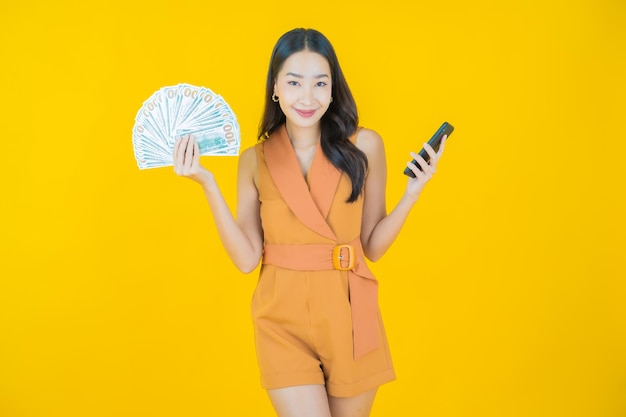 많은 현금과 돈으로 웃는 아름다운 젊은 아시아 여성의 초상화