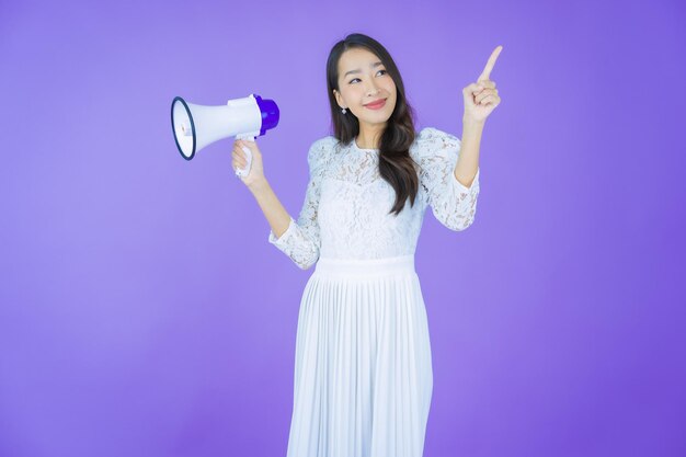 Улыбка женщины портрета красивая молодая азиатская с мегафоном на предпосылке цвета
