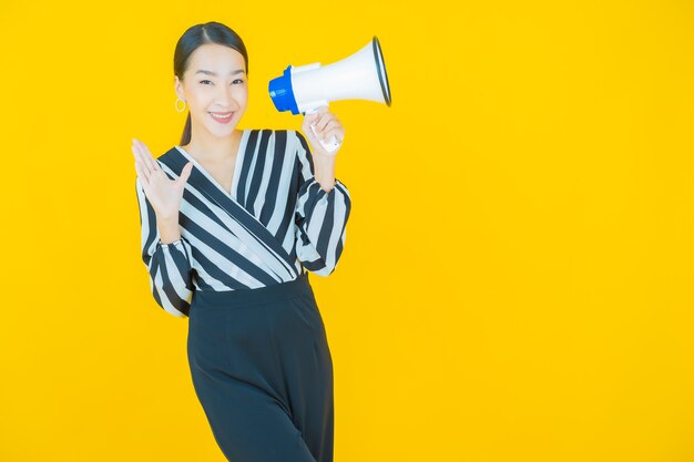 黄色のメガホンで笑顔美しい若いアジアの女性の肖像画