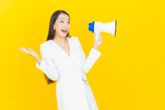 Free Photo portrait beautiful young asian woman smile with megaphone on yellow color background
