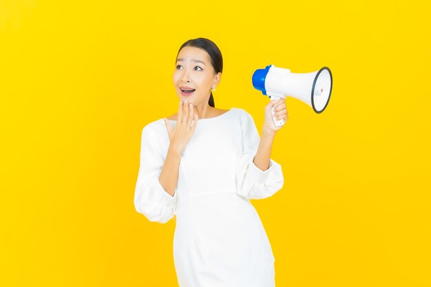 Portrait beautiful young asian woman smile with megaphone on yellow