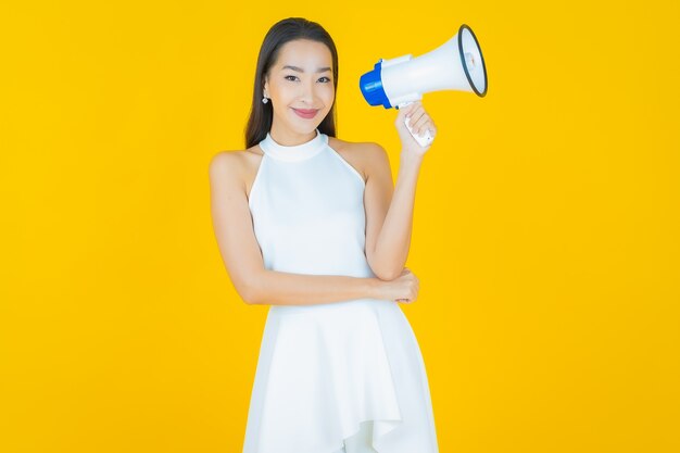 Portrait beautiful young asian woman smile with megaphone on yellow