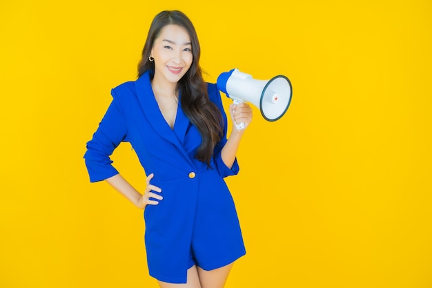 Portrait beautiful young asian woman smile with megaphone on yellow