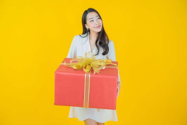 Portrait beautiful young asian woman smile with red gift box on color background