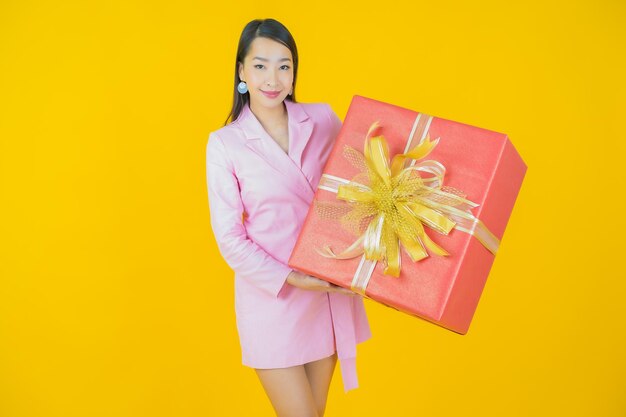 Portrait beautiful young asian woman smile with red gift box on color background