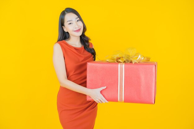 노란색에 빨간 선물 상자와 함께 초상화 아름 다운 젊은 아시아 여자 미소