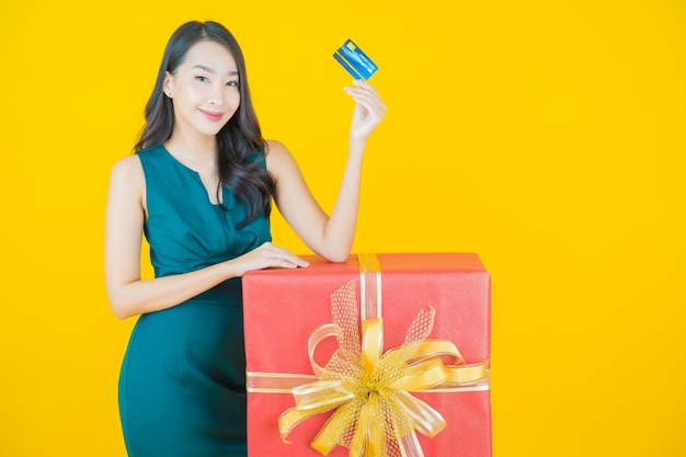 Portrait beautiful young asian woman smile with red gift box on yellow