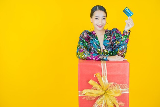 Portrait beautiful young asian woman smile with red gift box on yellow