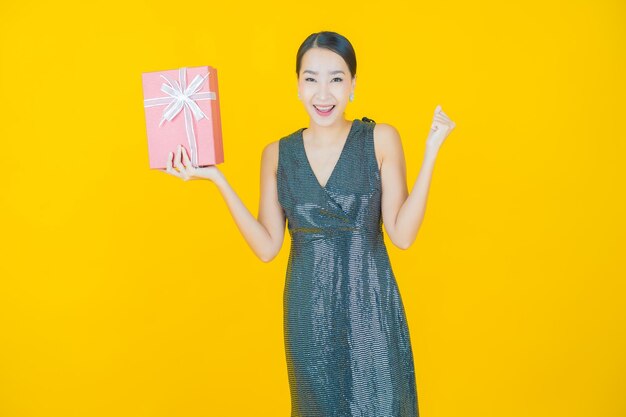 Portrait beautiful young asian woman smile with red gift box on yellow