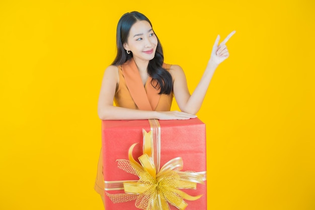 Портрет красивой молодой азиатской улыбки женщины с красной подарочной коробкой