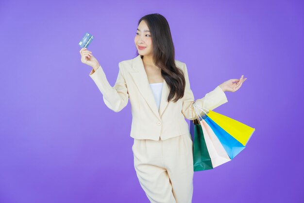 肖像画美しい若いアジアの女性が色の背景に買い物袋で笑顔