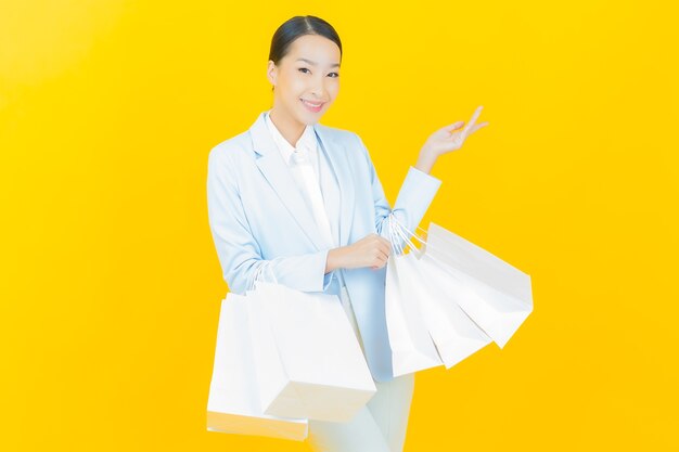 노란색에 쇼핑백을 들고 웃는 아름다운 젊은 아시아 여성 초상화