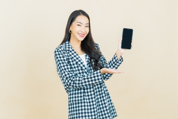 ベージュのスマート携帯電話で笑顔のポートレート美しい若いアジア女性