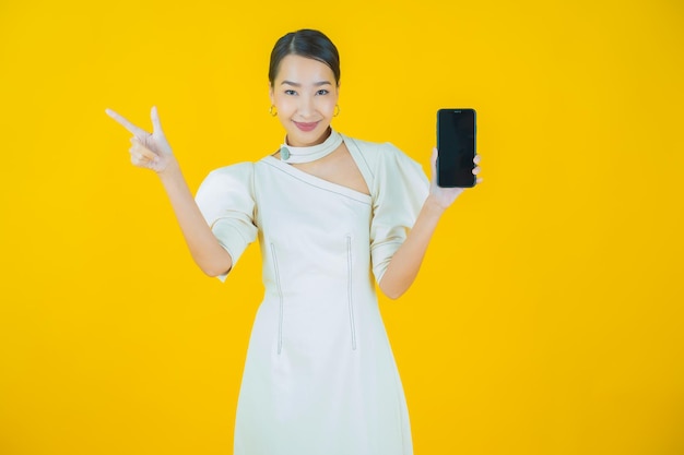 Ritratto di una bella giovane donna asiatica che sorride con un telefono cellulare intelligente su uno sfondo colorato