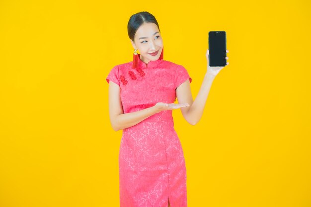 Улыбка женщины портрета красивая молодая азиатская с умным мобильным телефоном на цветном фоне